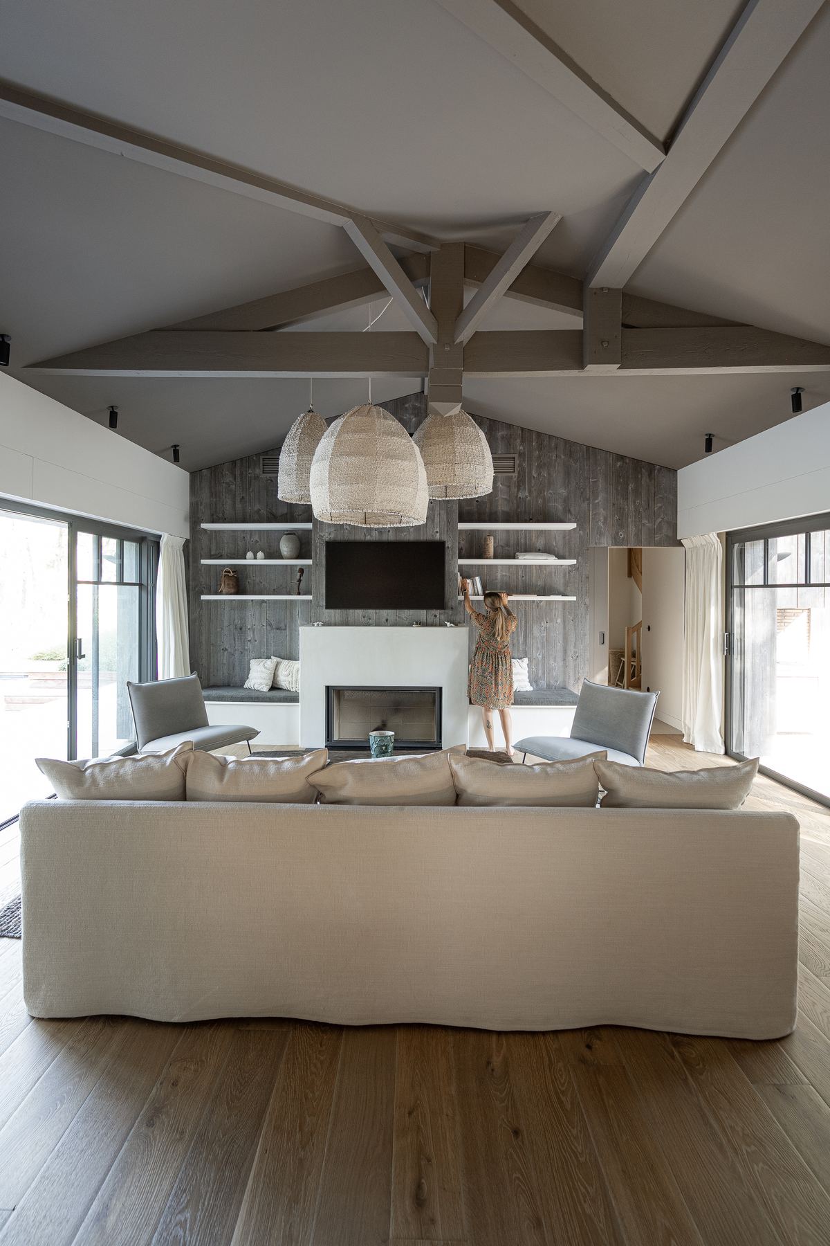 Salon sous charpente apparente avec cheminée, villa du Bassin d'Arcachon photographiée par Maison Òstra