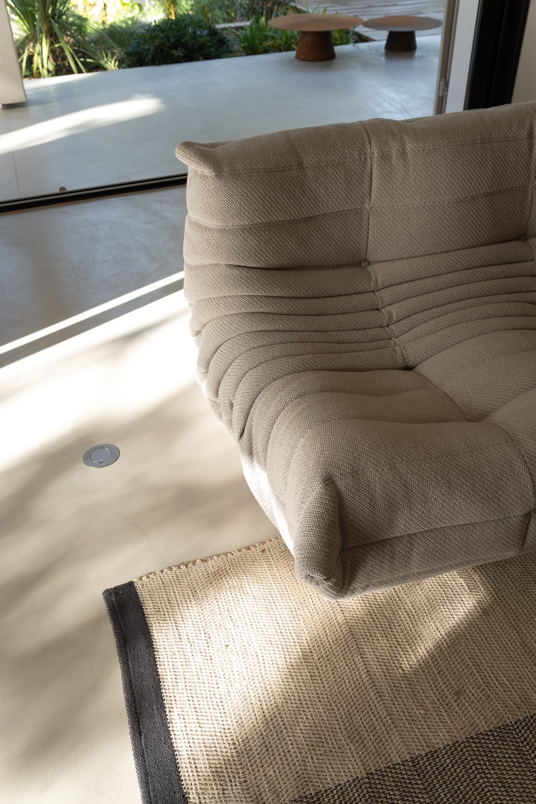 Détail d'un canapé en contre-jour et des ombres portées d'une baie vitrée, photographie d'intérieur