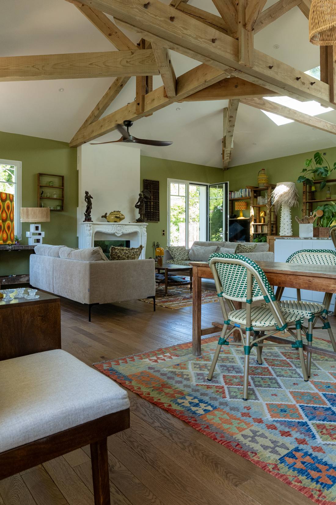 Salon sous charpente apparente avec tapis berbère et table de repas, maison rénovée à Arcachon